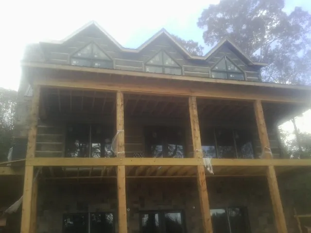 Dormers and porch framing on a large log home under construction — Roof Coating work by our crew in Gonzales