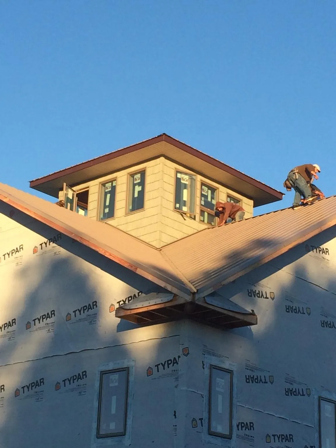 Roofers working around a rooftop cupola on a new metal roof at sunset — Roof Waterproofing in Gonzales by Roofing Brothers